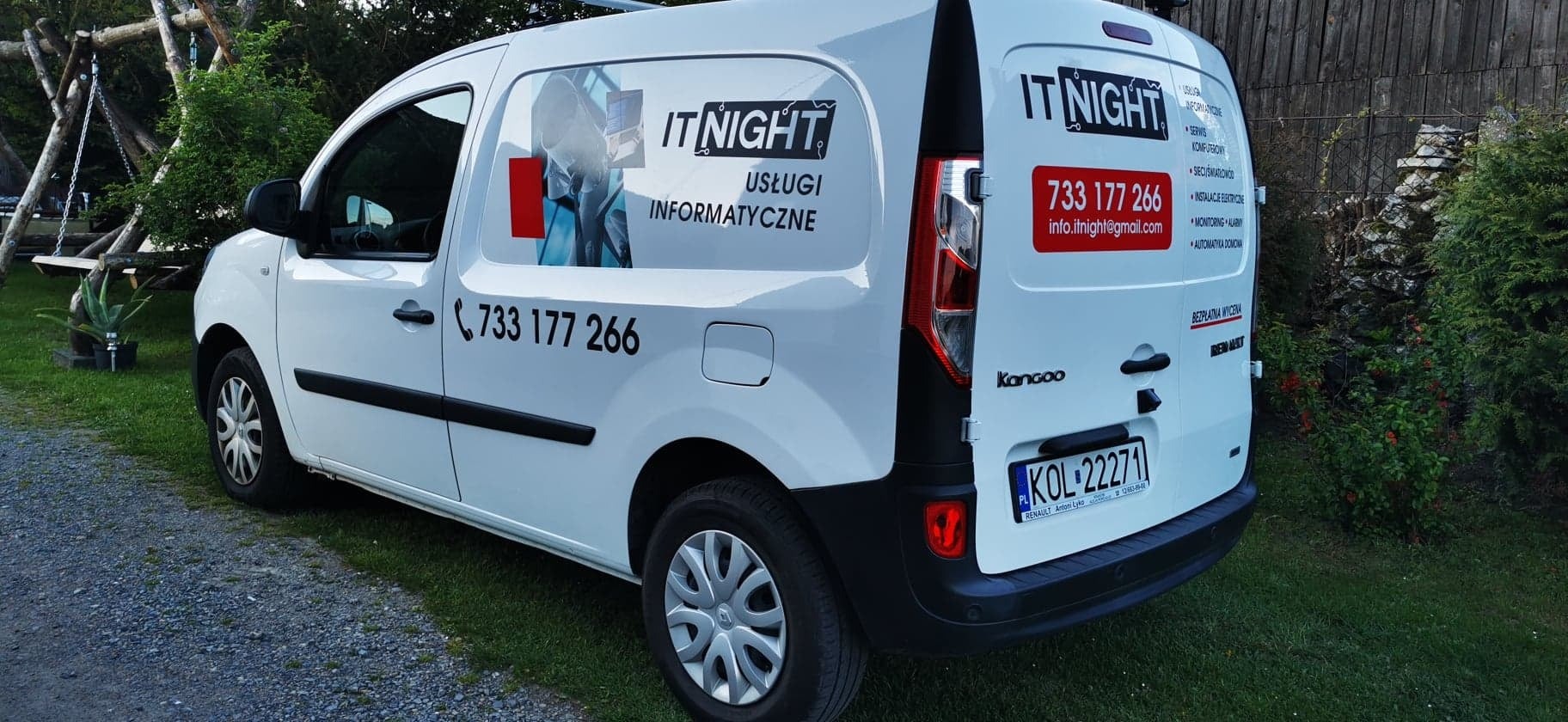 Biały samochód dostawczy z logo firmy IT NIGHT i numerem telefonu 733 177 266, zaparkowany na trawie, oferujący usługi informatyczne, serwis komputerowy i sieci światłowodowe.