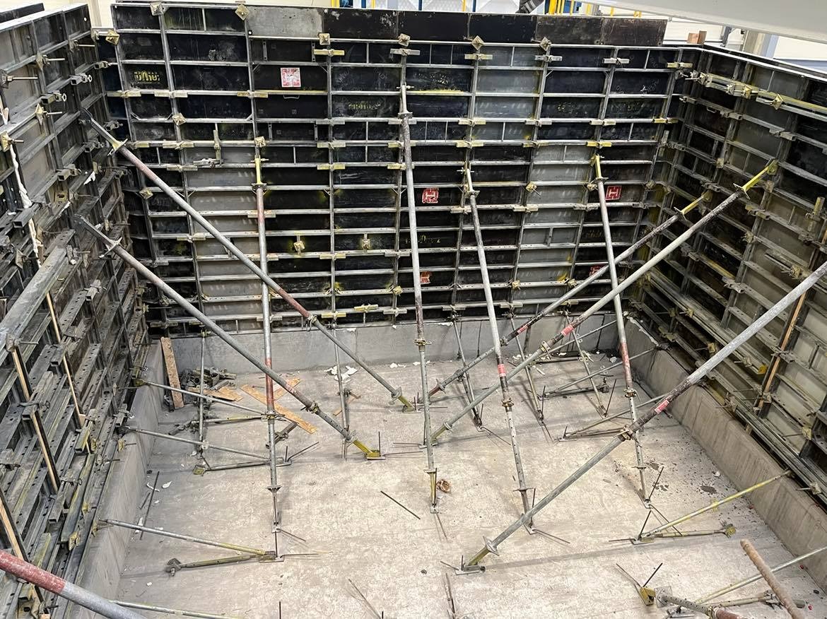 Szare szalunki wzmocnione metalowymi podporami, przygotowane do wylania betonu, widok z góry na plac budowy.