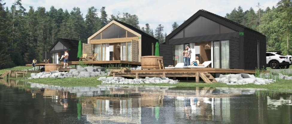 Wizualizacja trzech nowoczesnych domków letniskowych z czarną elewacją i dużymi przeszkleniami, położonych nad brzegiem jeziora i otoczonych lasem, z drewnianymi tarasami i jacuzzi na zewnątrz.