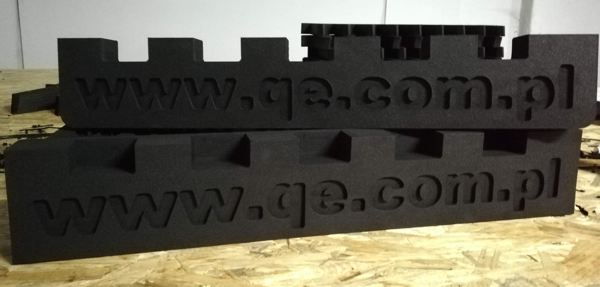 Czarne piankowe kształtki z wyciętym adresem strony internetowej ułożone jedna na drugiej, widoczne wycięcia w kształcie wieżyczek zamku.