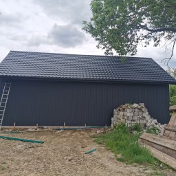 Budowa budynku garażowego. Konstrukcja drewniana, obłożona blachą T7, dach blachodachówka Karpatia, kolor antracytowy 7016 mat. Lokalizacja Szczebrzeszyn.