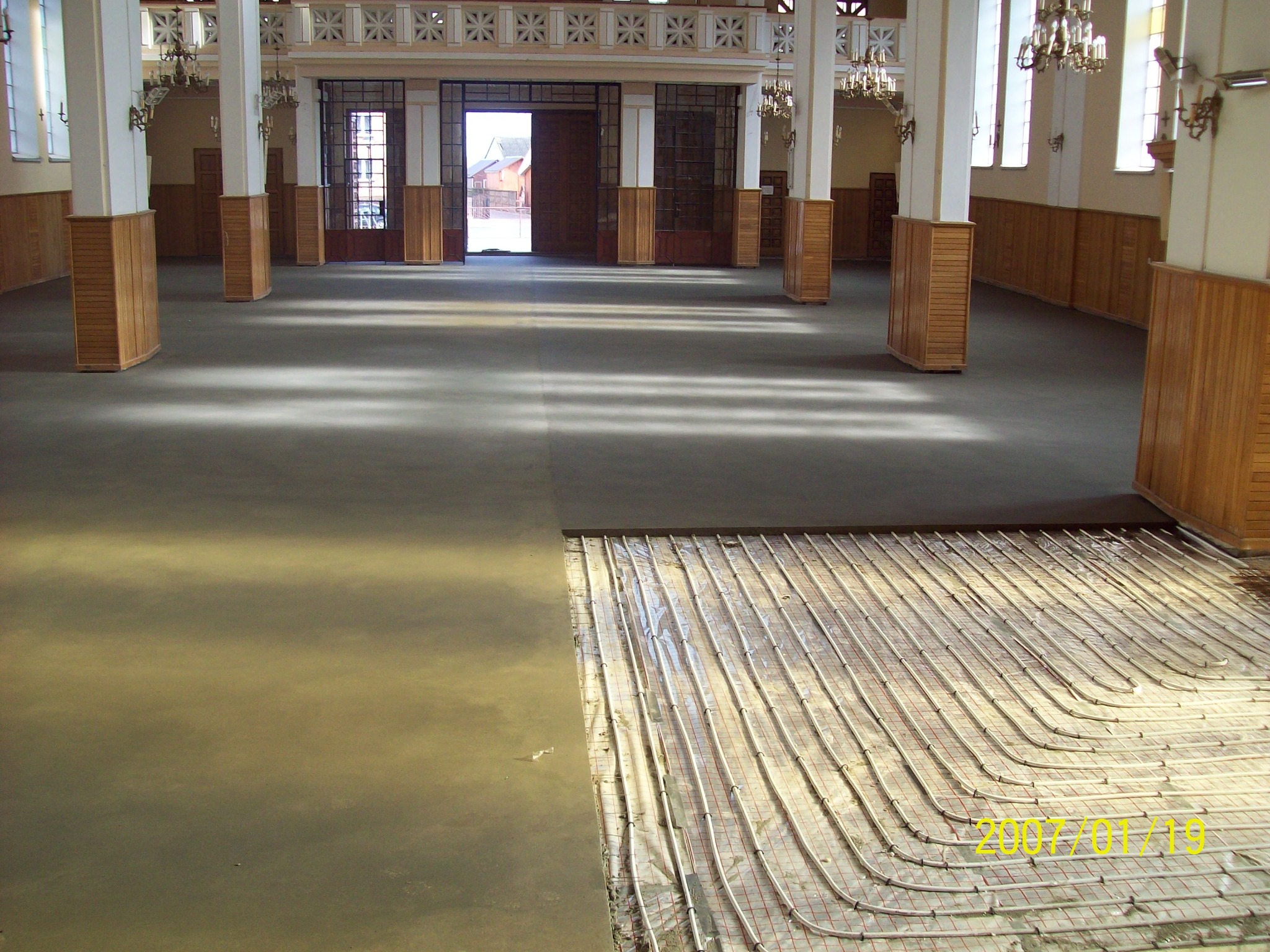 Wnętrze sali z widocznym fragmentem wylewki jastrychowej, z odsłoniętym systemem ogrzewania podłogowego, rurki grzewcze ułożone na siatce, data 2007/01/19 widoczna w prawym dolnym rogu.