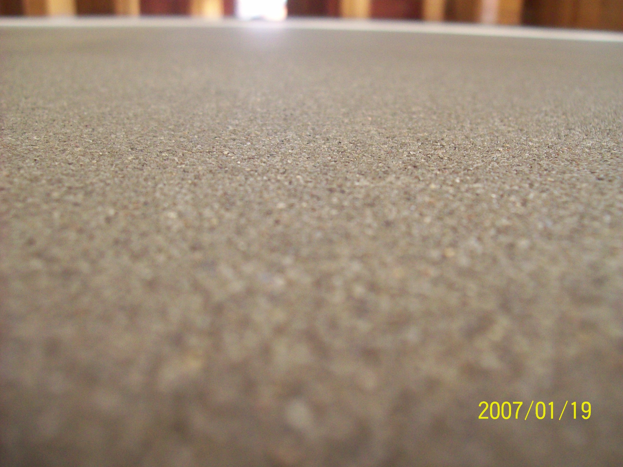 Szlifowana, beżowa powierzchnia podłogi z widoczną drobną strukturą, sfotografowana z niskiej perspektywy, z datą 2007/01/19 w prawym dolnym rogu.
