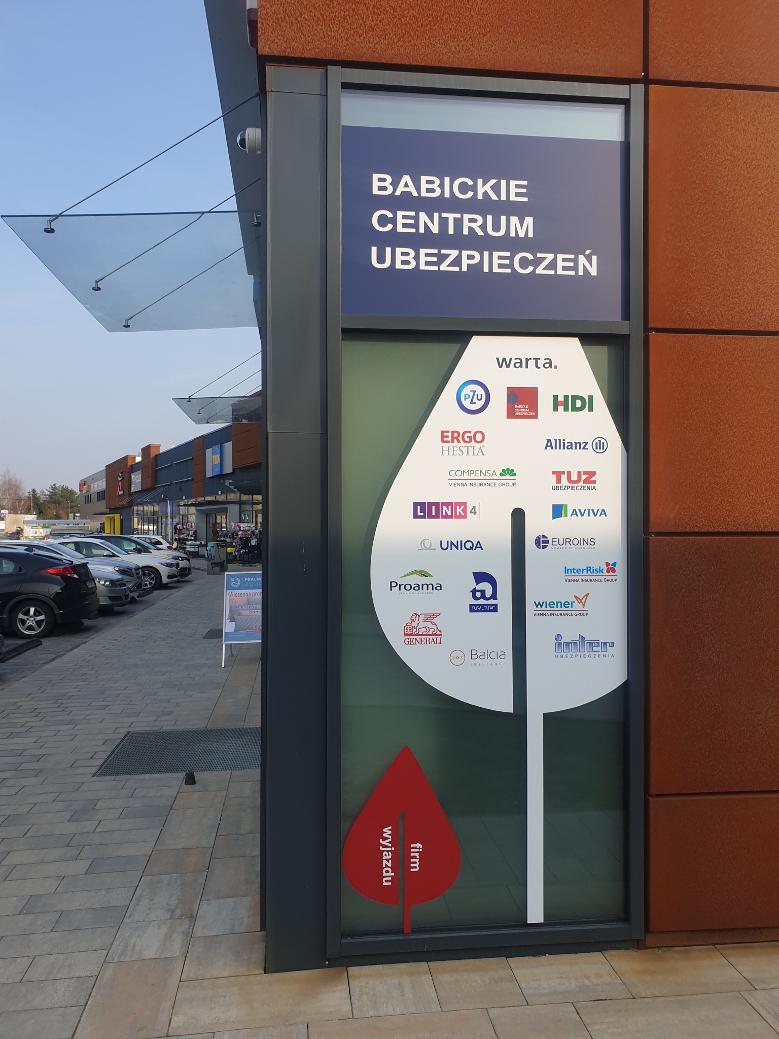 Budynek z szyldem 'Babickie Centrum Ubezpieczeń' prezentującym logotypy różnych towarzystw ubezpieczeniowych, widok z zewnątrz.