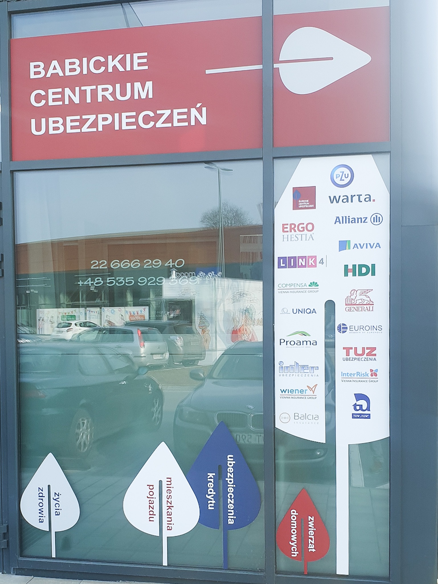 Fasada biura Babickie Centrum Ubezpieczeń z logo firm ubezpieczeniowych i informacją o rodzajach oferowanych polis: zdrowia, życia, mieszkania, pojazdów, kredytów i zwierząt.