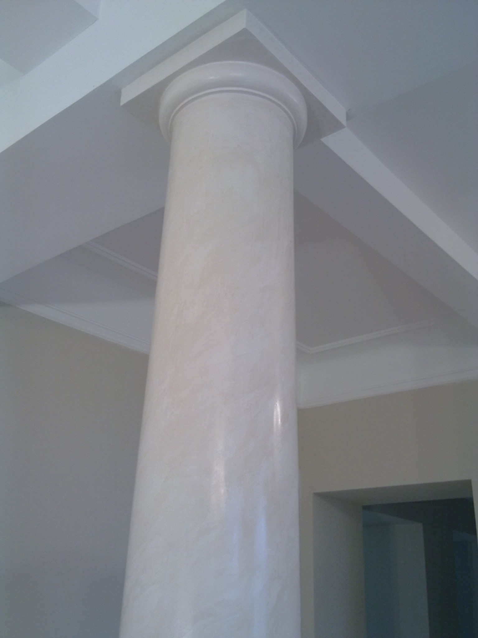 Wnętrze z kolumną wykończoną gładzią imitującą marmur, widoczny fragment sufitu z dekoracyjnymi elementami.
