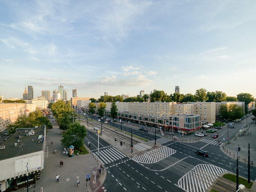Panorama miasta z widokiem na bloki mieszkalne, ulice z przejściami dla pieszych i odległe wieżowce w letni dzień.