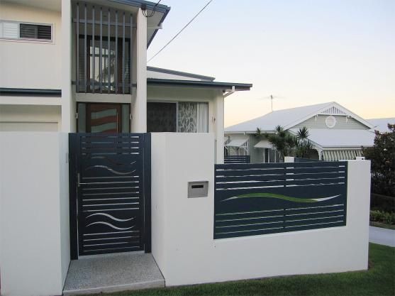 Nowoczesna, pozioma brama i przęsło z metalowych profili w kolorze grafitowym, z motywem fal, wkomponowane w białe, murowane ogrodzenie domu.