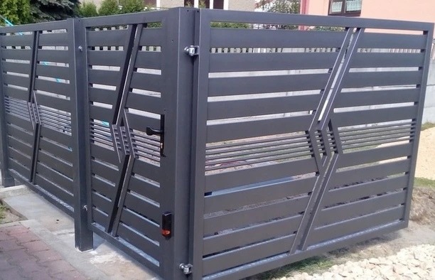 Nowoczesna brama wjazdowa z poziomych profili w kolorze grafitowym, z ukośnymi wzmocnieniami i czarną klamką, widok z zewnątrz posesji.