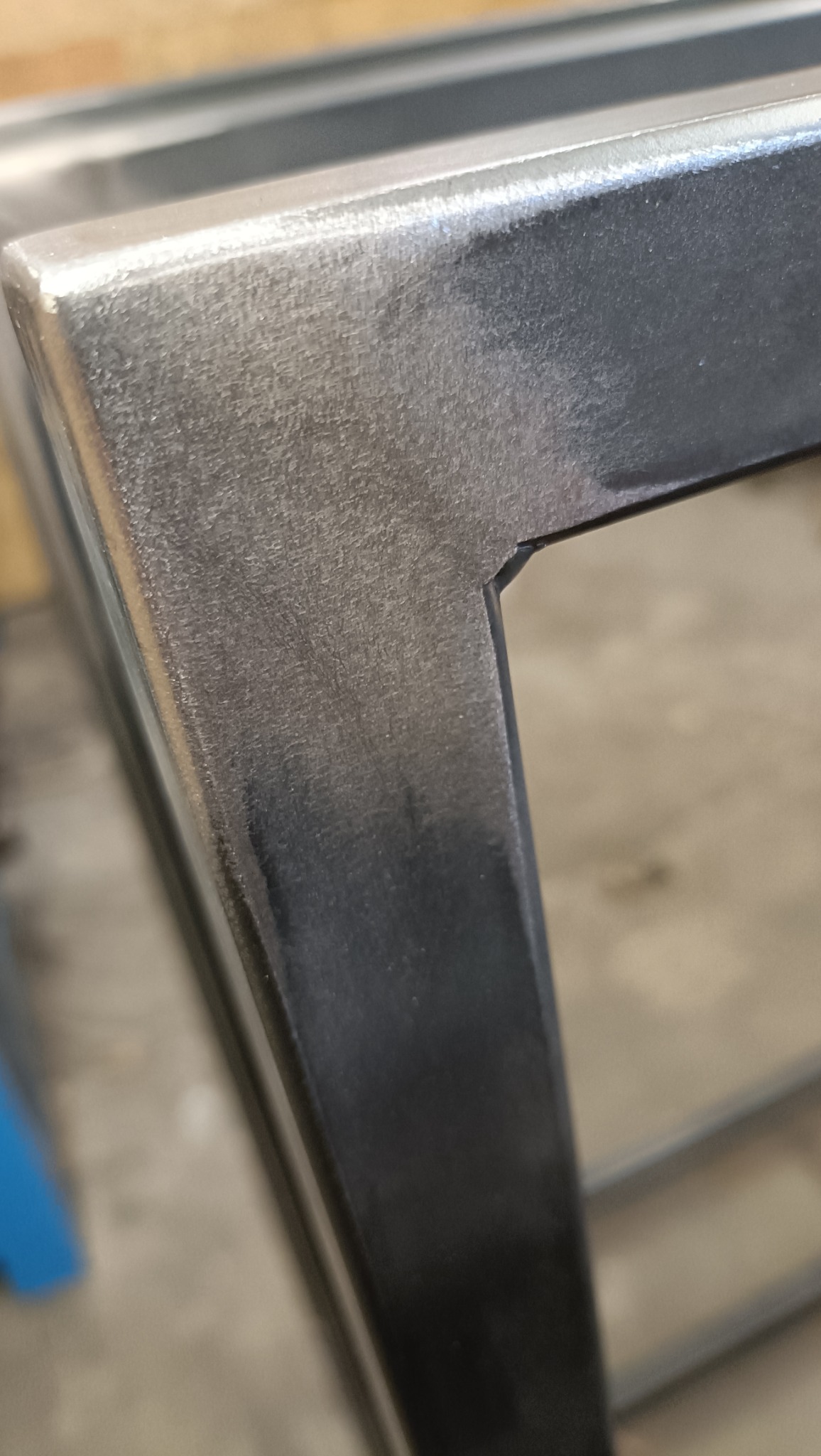 Szczegółowe ujęcie spawu na rogu metalowej konstrukcji, widoczna faktura metalu i precyzyjne połączenie elementów.