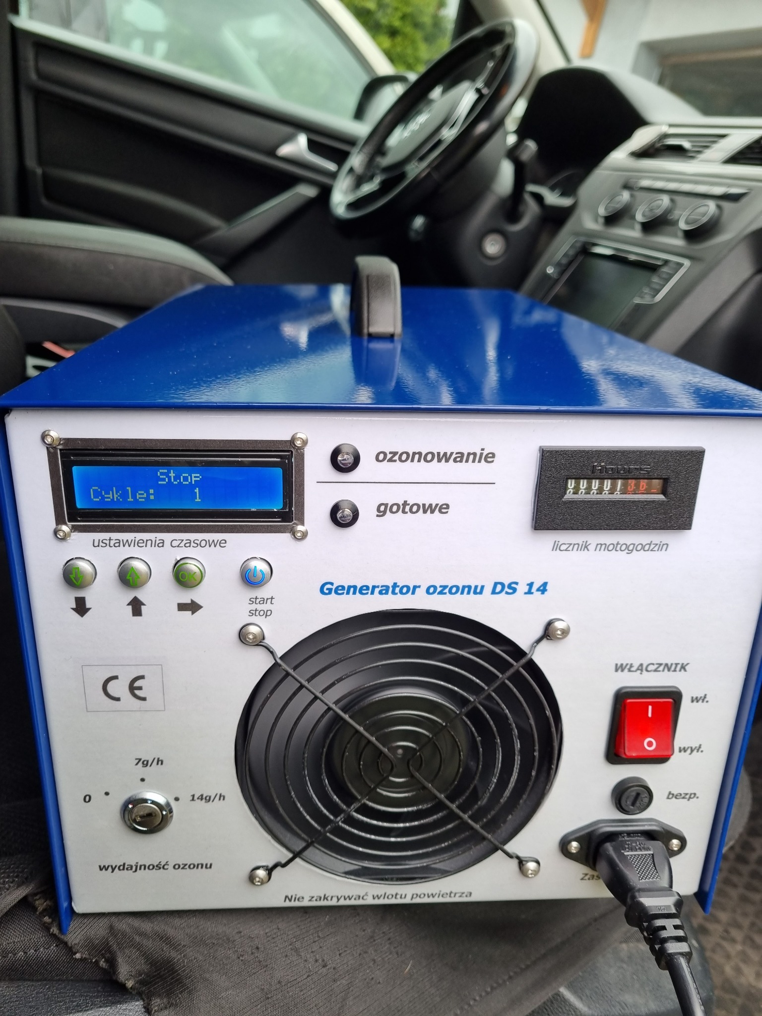 Generator ozonu DS 14 w kabinie samochodu, widoczny panel sterowania z wyświetlaczem LCD wskazującym cykl ozonowania, włącznik, licznik motogodzin i regulacja wydajności ozonu.
