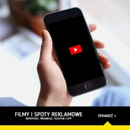Osoba trzyma smartfon z wyświetlonym logo YouTube na czarnym ekranie, w tle widoczne okno.