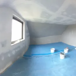 Poddasze w Dominowie w trakcie szpachlowania: widoczne okna, ściany i sufit pokryte gładzią szpachlową, podłoga zabezpieczona folią, drabina i wiaderka z materiałami.