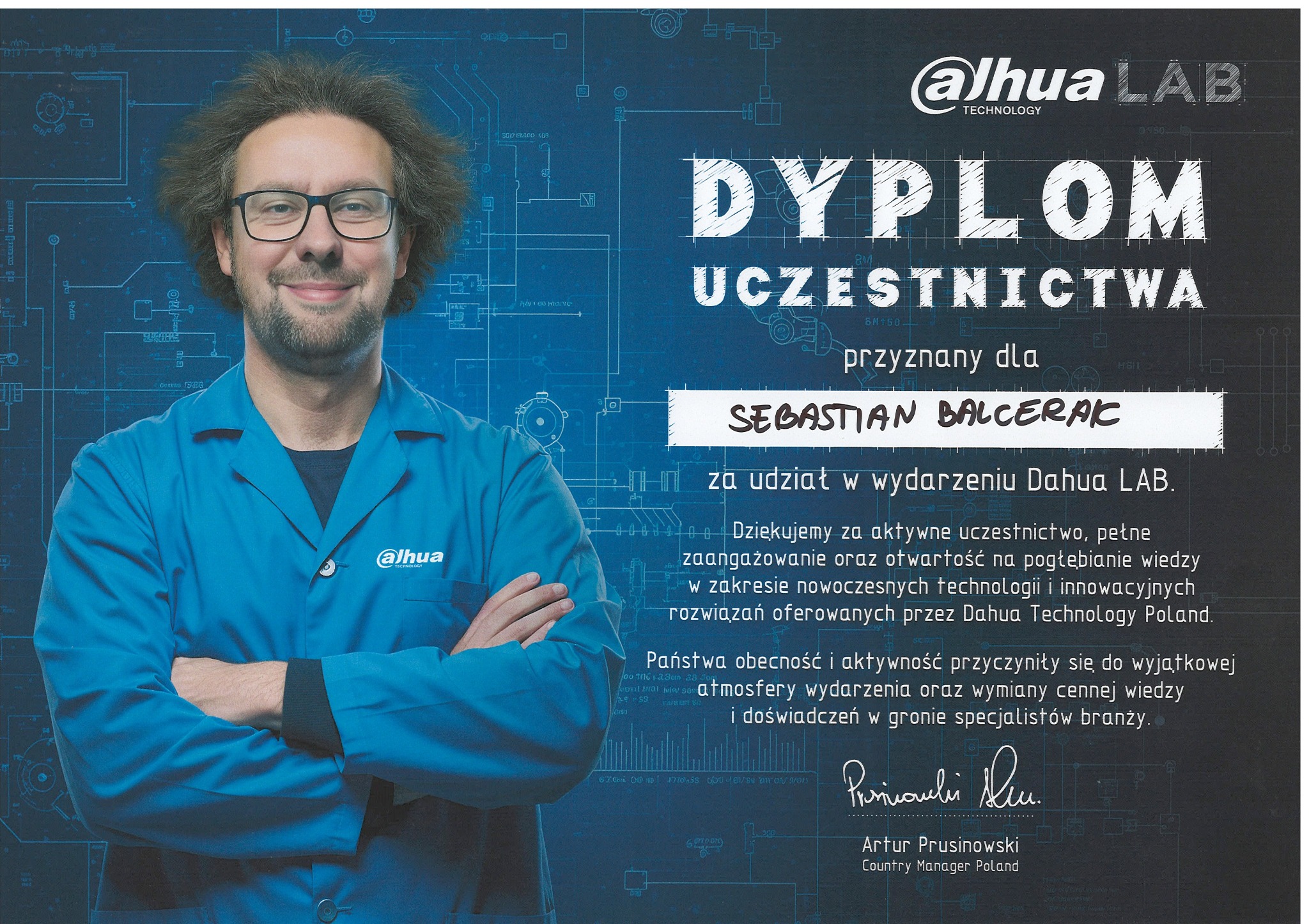 Portret mężczyzny w niebieskim uniformie na tle dyplomu uczestnictwa Dahua Lab, z widocznym logo firmy i podpisem Artura Prusinowskiego.