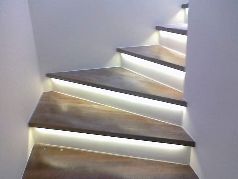 Schody drewniane z podświetleniem LED wzdłuż stopni, widok z dołu, minimalistyczny design.