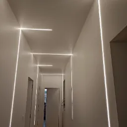 Korytarz z minimalistycznym oświetleniem LED wbudowanym w ściany i sufit, tworzącym geometryczny wzór.