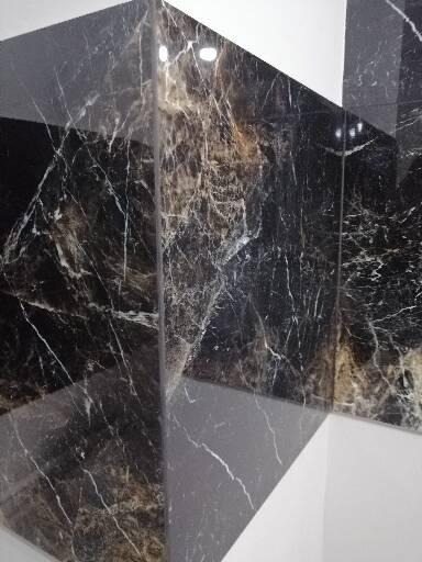 Ściana wyłożona czarnymi, błyszczącymi płytkami imitującymi marmur z białymi żyłkami, narożnik w Żninie.