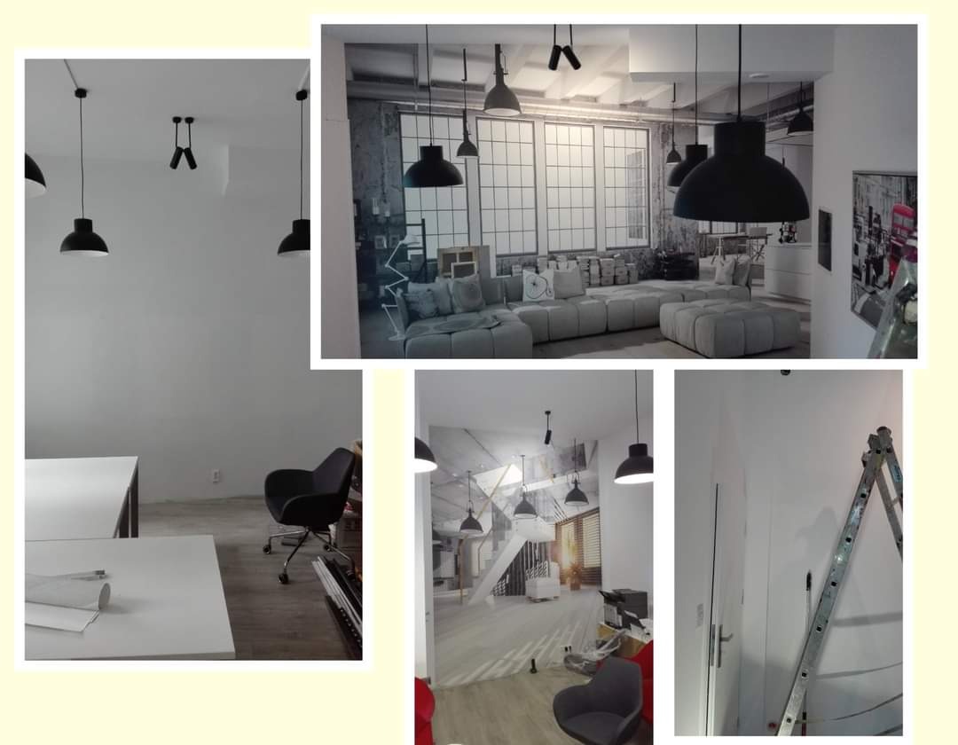 Wnętrze biura w trakcie malowania, z widoczną drabiną opartą o ścianę, biurkiem z rozłożonymi planami i fototapetą z motywem loftowym na ścianie w tle.