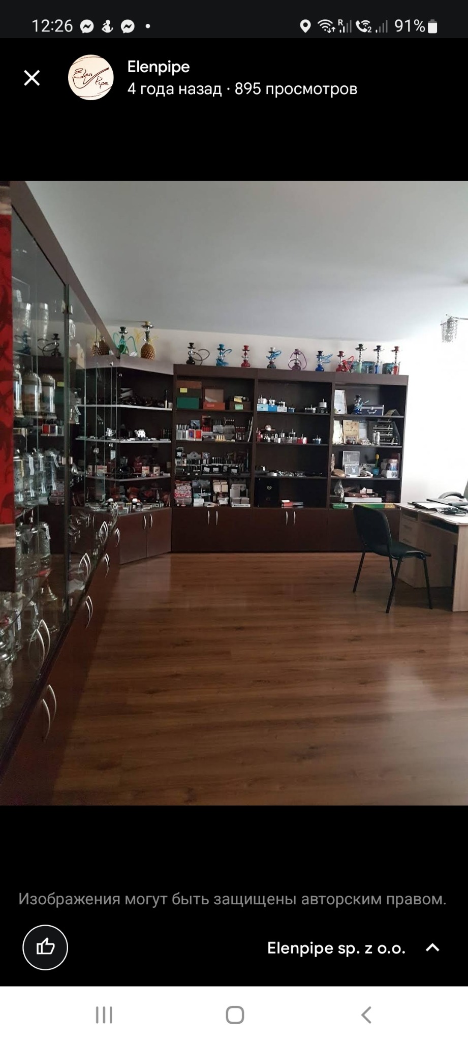 Wnętrze sklepu z akcesoriami do palenia, widoczne szklane gabloty i półki z różnorodnymi fajkami wodnymi, tytoniem i innymi akcesoriami, drewniana podłoga.