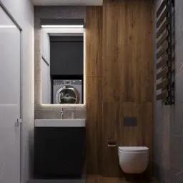 Nowoczesna łazienka z podświetlanym lustrem, umywalką z czarną szafką, drewnianą okładziną ścienną i widoczną pralką w głębi.