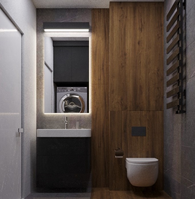 Nowoczesna łazienka z podświetlanym lustrem, umywalką z czarną szafką, drewnianą okładziną ścienną i widoczną pralką w głębi.