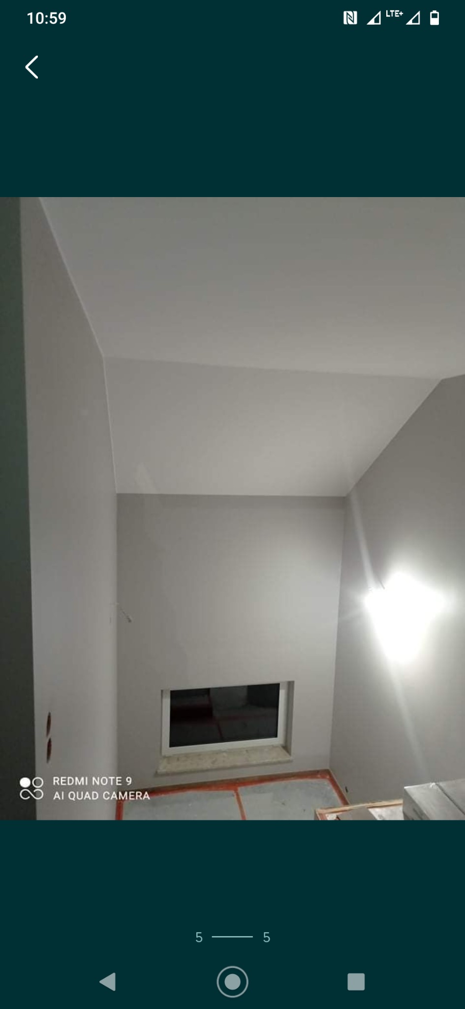 Pomieszczenie po malowaniu ścian na szaro i biało, widoczne okno z marmurowym parapetem, podłoga zabezpieczona folią malarską, dwa otwory na gniazdka elektryczne po lewej stronie.