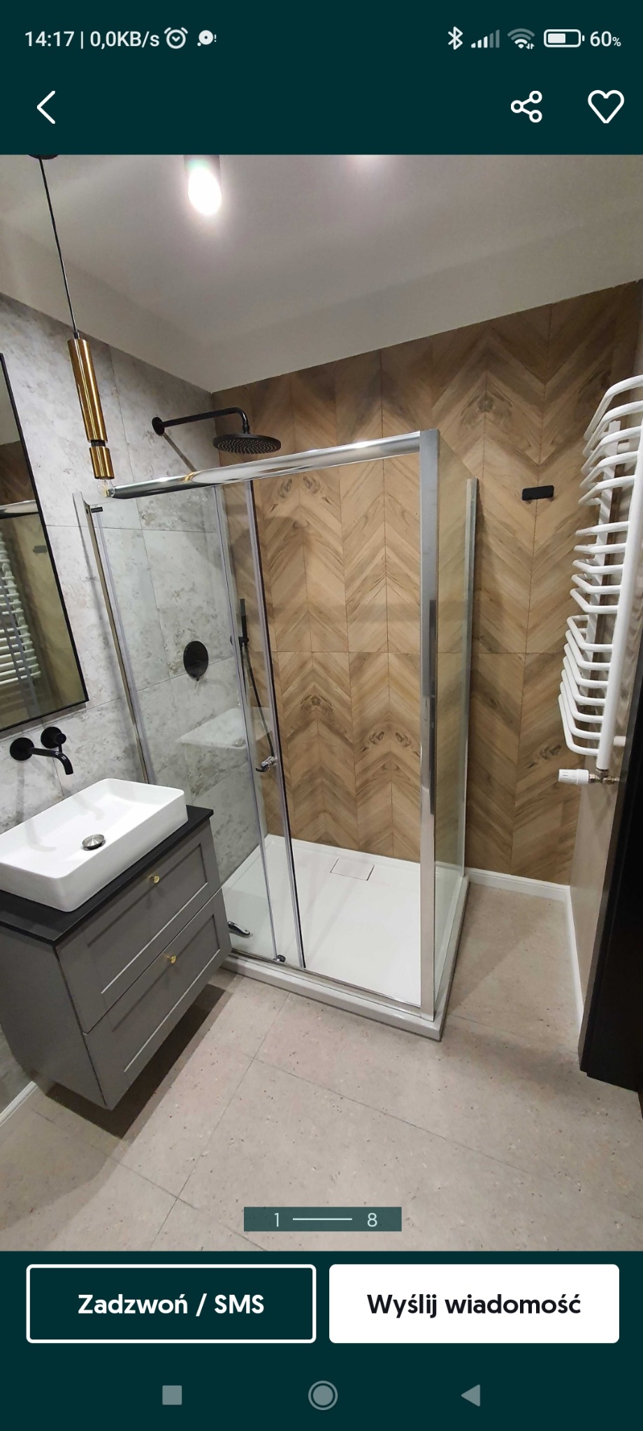 Nowoczesna łazienka z kabiną prysznicową, umywalką nablatową na szafce z szufladami, oraz grzejnikiem drabinkowym na ścianie z drewnopodobnymi płytkami ułożonymi w jodełkę.