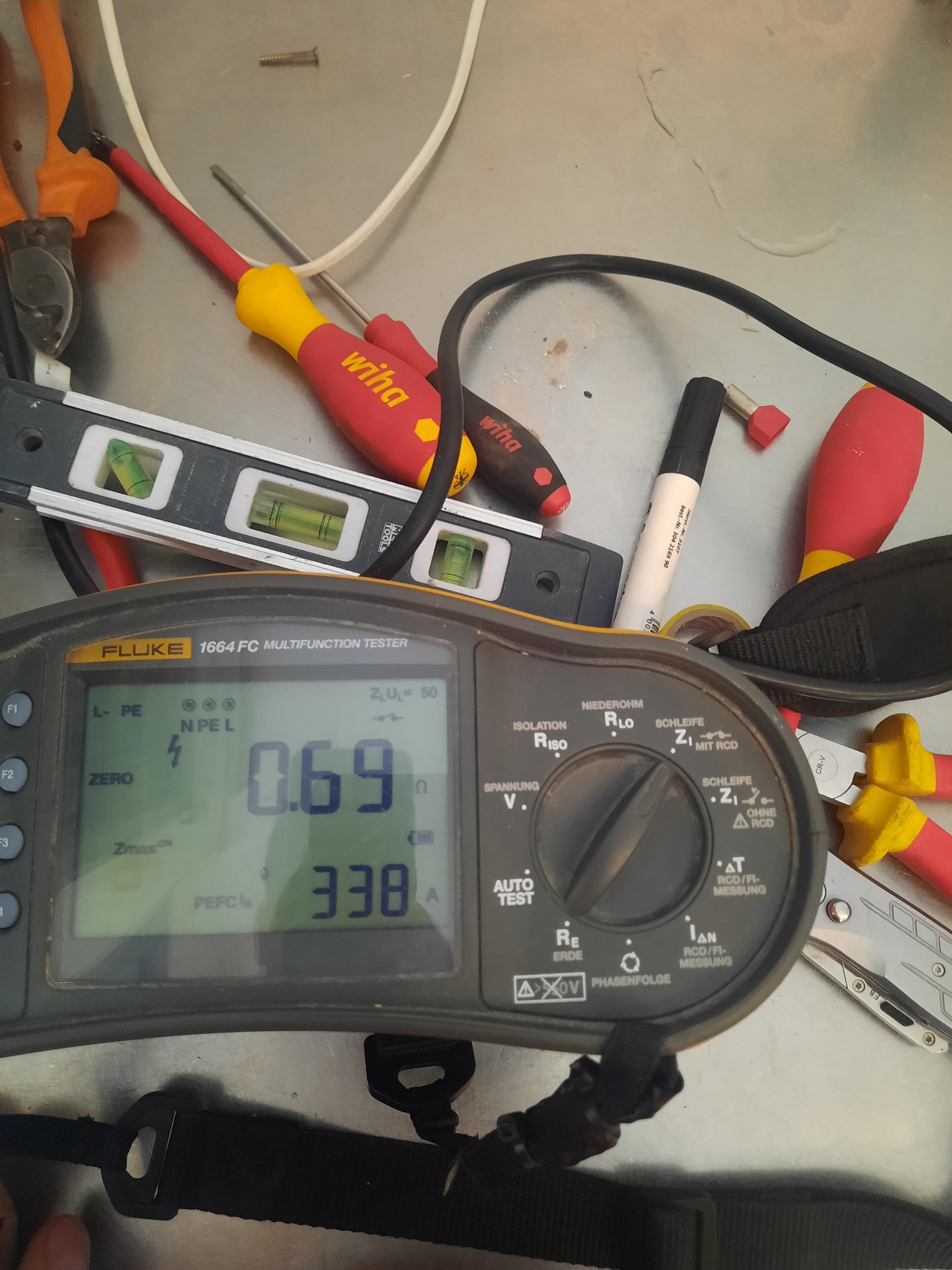 Miernik Fluke 1664 FC i narzędzia elektryczne, w tym poziomica i śrubokręty Wiha, na metalowym stole w Słupsku, sugerujące pomiary elektryczne.