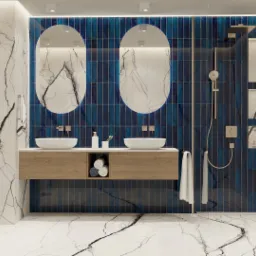 Nowoczesna łazienka z marmurowymi ścianami i podłogą, granatowymi pionowymi płytkami za dwiema owalnymi umywalkami nablatowymi, drewnianą szafką pod umywalkami z ręcznikami, kabiną prysznicową typu...