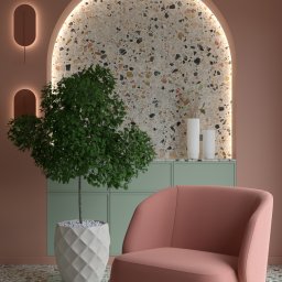 ProReal Studio Justyna Kępa - Stylowe wnętrze z różowym fotelem na tle ściany z terazzo, podświetlonego łukiem. Obok zielona szafka i roślina w ozdobnej donicy. Nowoczesny design.