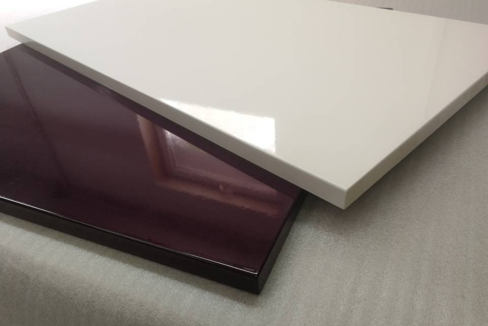 Dwie lakierowane płyty meblowe: biała i w kolorze ciemnej śliwki, ułożone jedna na drugiej, prezentujące połyskliwe wykończenie.
