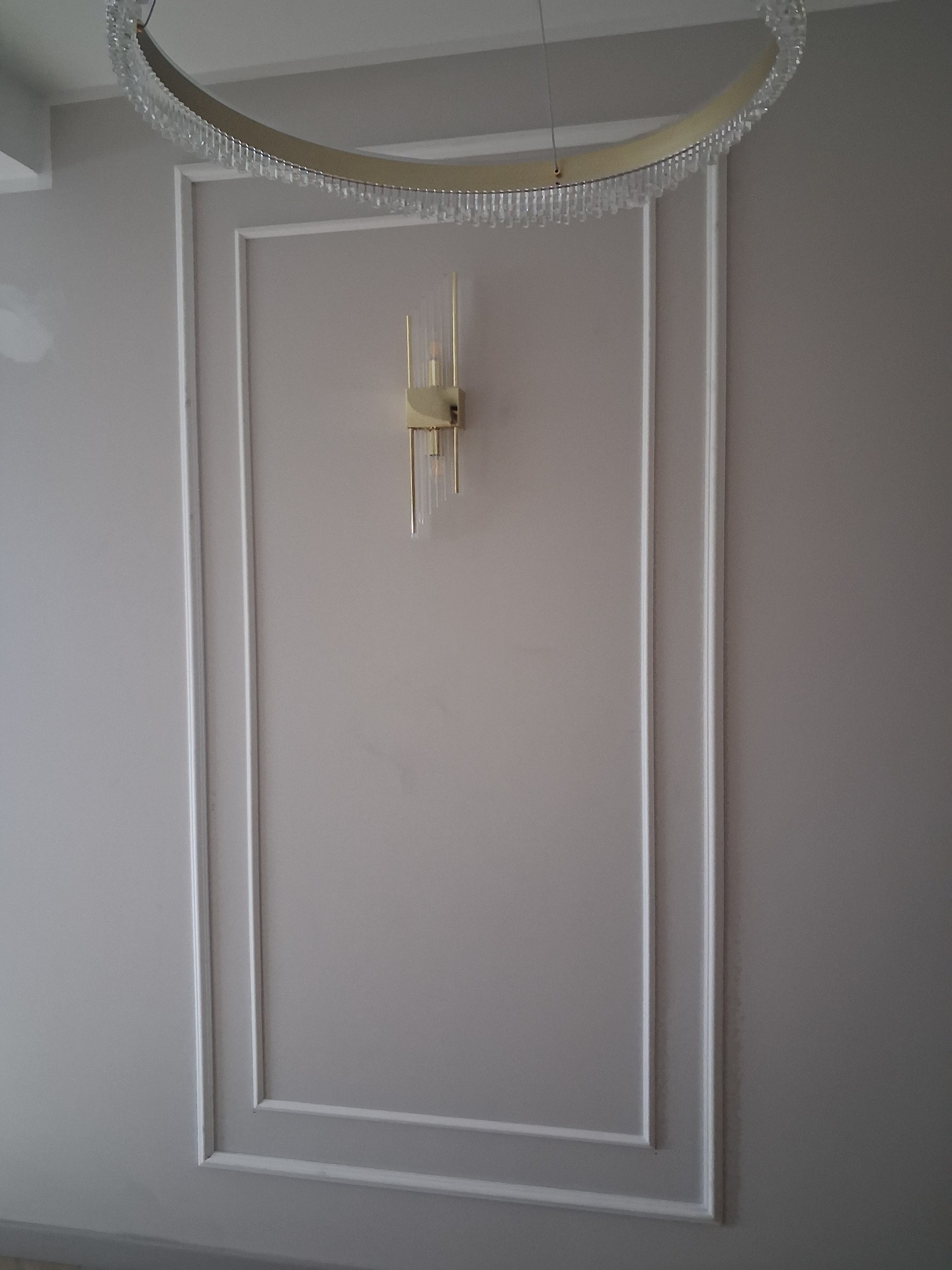 Dekoracyjna ściana z ramą i oświetleniem w Nakle nad Notecią. Subtelne zdobienia i nowoczesna lampa ścienna tworzą elegancki detal wnętrza.