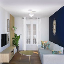 Iga Paśnicka - Jasny salon z drewnianymi akcentami, roślinami doniczkowymi i granatową ścianą z dekoracyjnym lustrem w kształcie słońca.