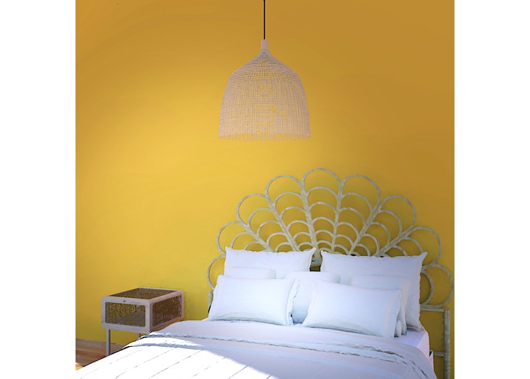 Żółta sypialnia z dekoracyjnym wezgłowiem w kształcie wachlarza, białymi poduszkami i rattanową lampą wiszącą.