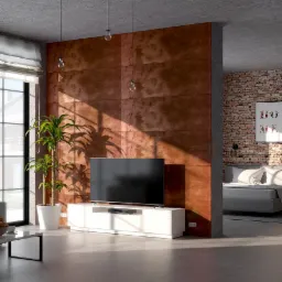 Nowoczesny salon z dekoracyjną ścianą z paneli w kolorze rdzawym, dzielącą przestrzeń na część dzienną i sypialnię z ceglaną ścianą, oświetlony popołudniowym słońcem wpadającym przez duże okno.