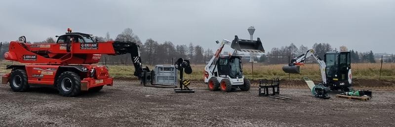 Zestaw maszyn budowlanych na placu: czerwony podnośnik teleskopowy, biała ładowarka i czarno-biała koparka, sprzęt do podnoszenia i zagęszczarka w tle, widoczna wieża ciśnień.