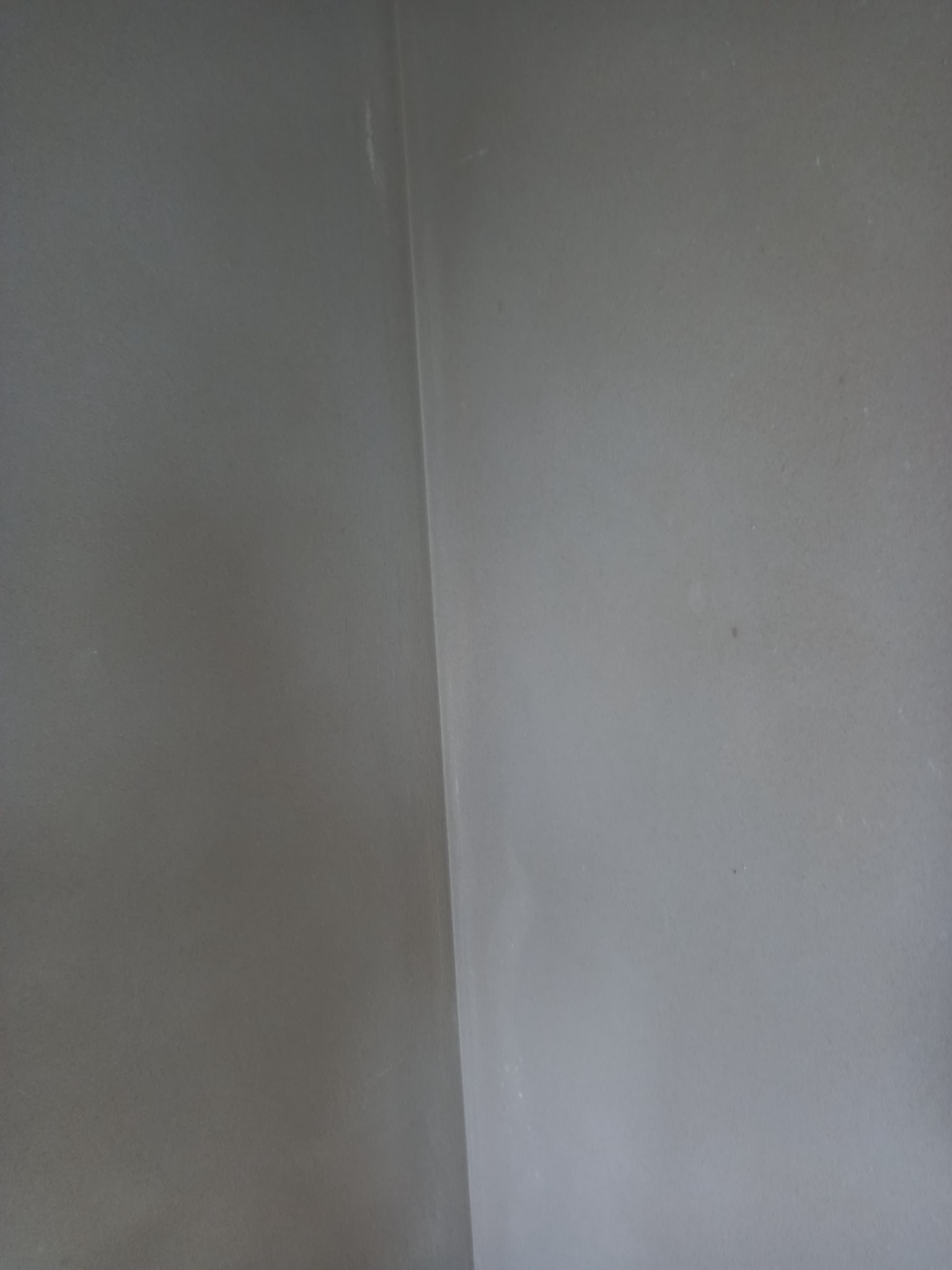 Gładka, szara ściana wewnętrzna po tynkowaniu, widoczna krawędź narożnika.