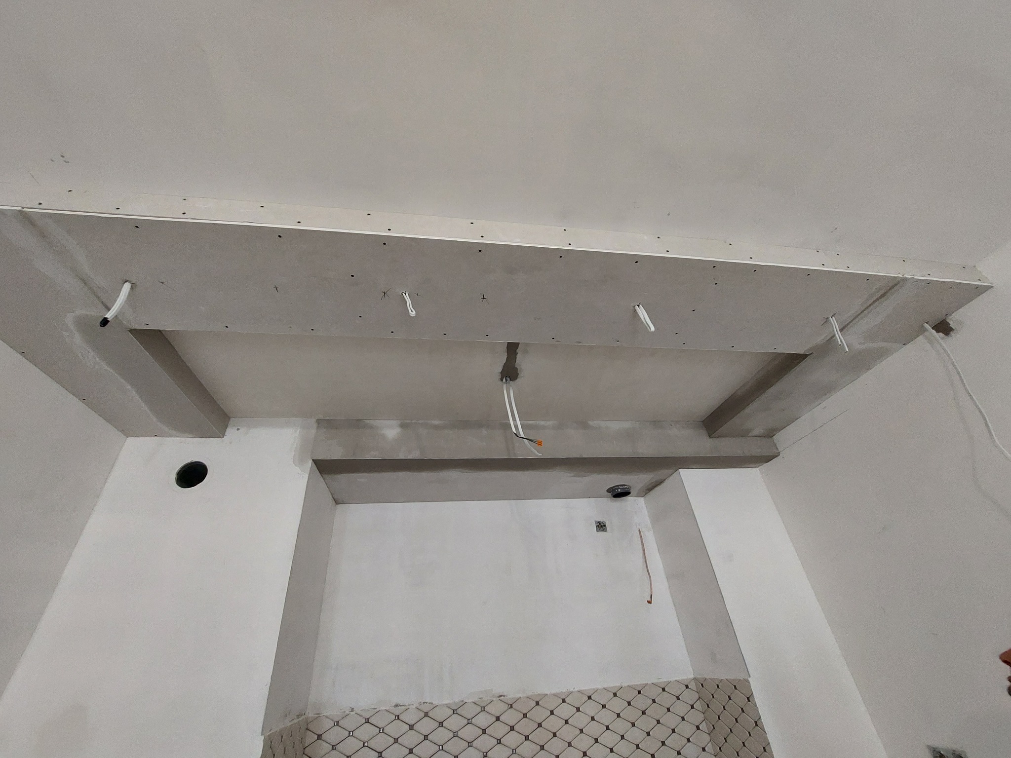 Konstrukcja sufitu podwieszanego z płyt gipsowo-kartonowych w trakcie montażu, widoczne przewody i elementy mocujące.