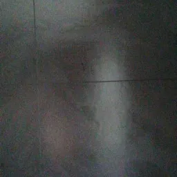 Ciemnobrązowe, błyszczące panele podłogowe z widocznymi łączeniami, słaba jakość zdjęcia.