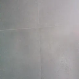 Szare, matowe płytki podłogowe ułożone z wąską fugą w jasnym odcieniu.