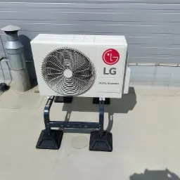 Zewnętrzna jednostka klimatyzacji LG Dual Inverter zamontowana na dachu, widoczny komin wentylacyjny w tle.