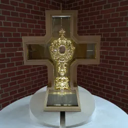 Krucyfiks z bogato zdobionym, złoconym relikwiarzem na marmurowym postumencie, tło z cegły