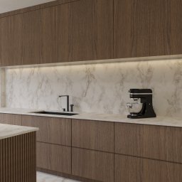 HouseOfDesign - Nowoczesna kuchnia z drewnianymi szafkami i marmurowym blatem. Czarny zlewozmywak i bateria, mikser stojący. Oświetlenie LED pod szafkami górnymi.