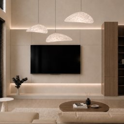 HouseOfDesign - Minimalistyczny salon z beżową ścianą, dużym telewizorem, trzema organicznymi lampami wiszącymi i podświetleniem LED. Drewniane szafki i okno z czarnymi żaluzjami.