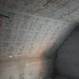 Poddasze z ociepleniem wełną mineralną z widoczną siatką wzmacniającą Stucanet i elementami instalacji elektrycznej w trakcie montażu.