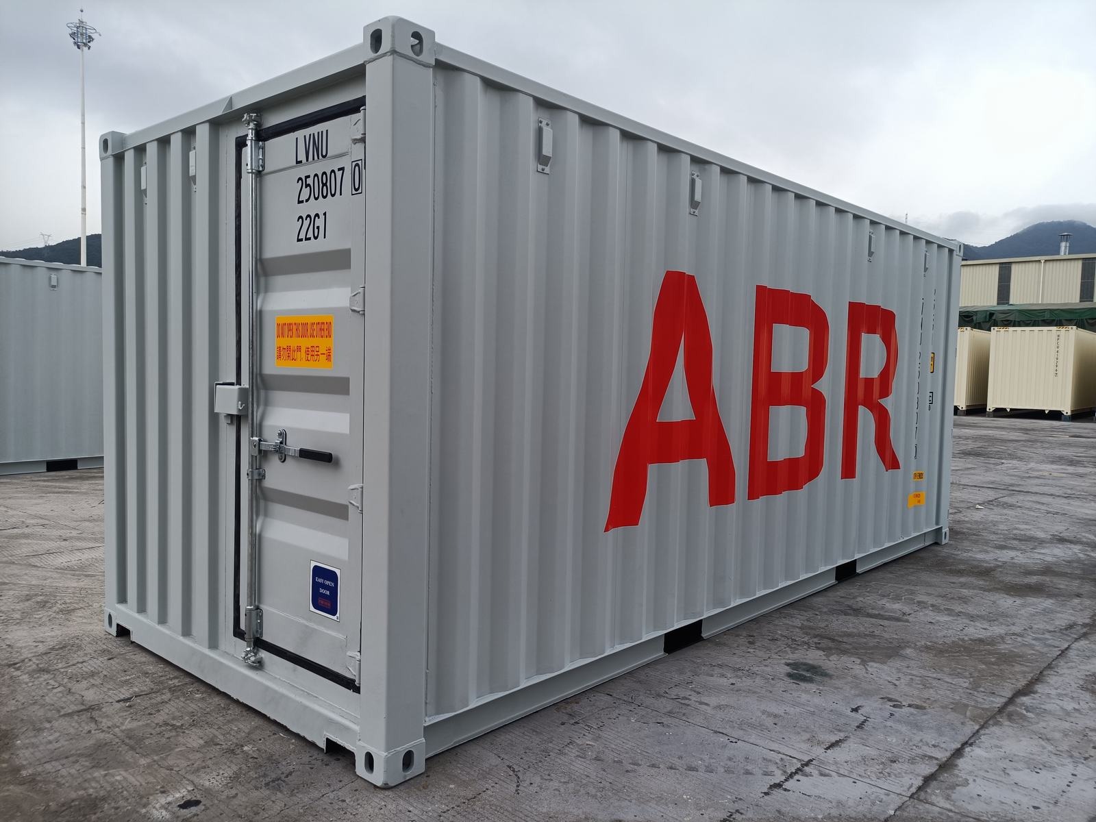 Szary kontener transportowy z czerwonym napisem ABR, widoczny numer seryjny i instrukcje obsługi drzwi.