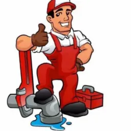 Karykaturalny hydraulik w czerwonym kombinezonie i czapce, trzymający klucz francuski, stojący na rurze, z uśmiechem i uniesionym kciukiem, obok czerwonej skrzynki narzędziowej.