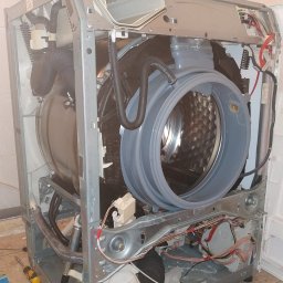 Serwis AGD w Szczecine - Pralka automatyczna z otwartą obudową, widoczne wnętrze bębna, elementy elektryczne i hydrauliczne, narzędzie w pobliżu