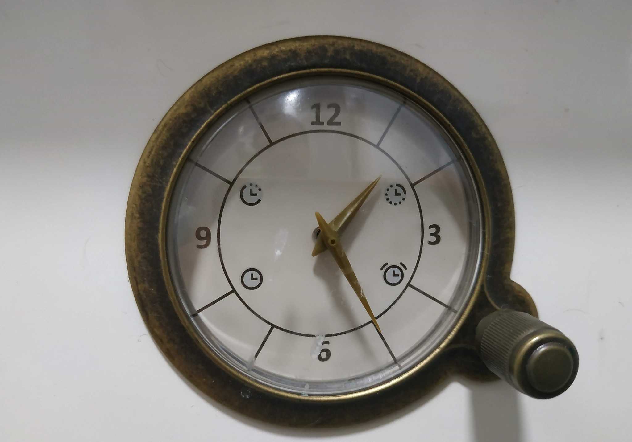 Zegar z brązową obudową wbudowany w białe urządzenie, prawdopodobnie panel sterowania sprzętu AGD, wskazujący godzinę 12:29.