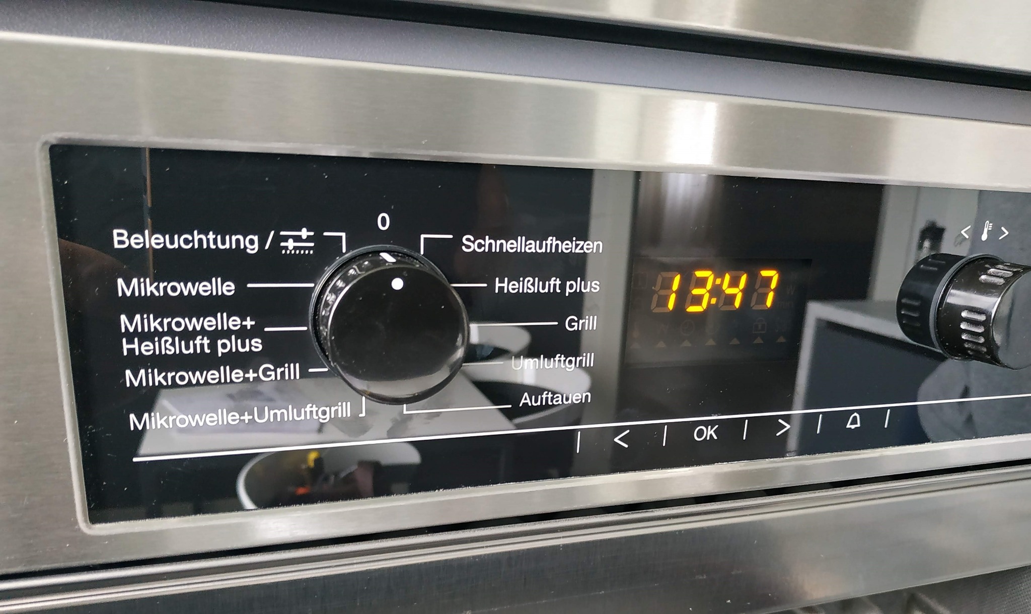 Panel sterowania piekarnika z ustawieniami funkcji, wyświetlaczem czasu i pokrętłami, z bliska.